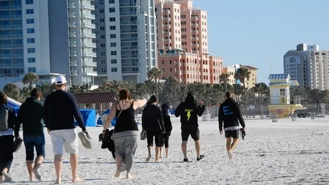 People Walking Down Beach On Cool Day  With Hotel Resorts Palm Trees In Back Stock Footage 127186404