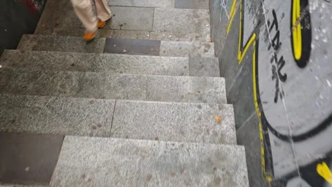 People walking down graffiti covered staircase Vidéo 310310541