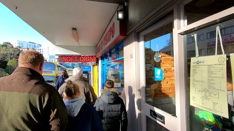 People walking down a street lined with posters advertising fish and chips, UK Stock Footage 200887431