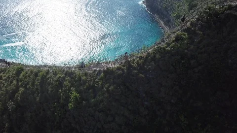 People Walking on Edge of Steep Cliff next to Beautiful Beach [Drone Footage] Stock Footage 96284561