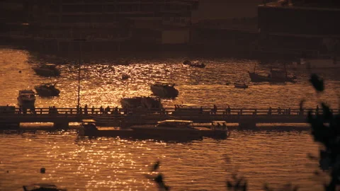 People walking on a footbridge, surrounded on both sides by the sea at sunset Video stock 237443655