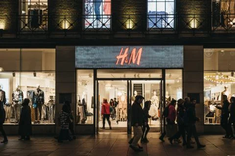 People walking in front of H&amp;M store on Oxford Street, London, UK, in the eve Stock Photos