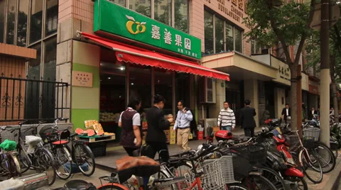 People walking in front of a vegetable shop in Shanghai Stock Footage 39593095