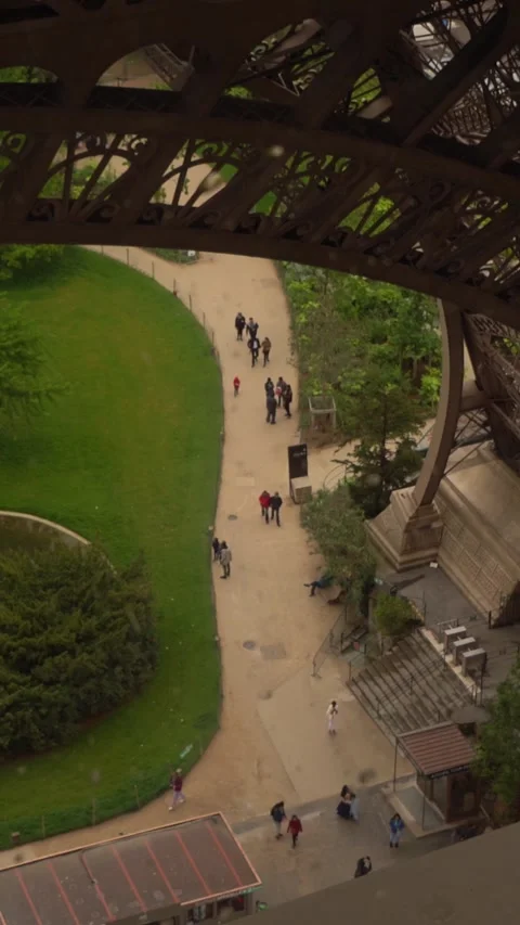 People Walking on Garden Path Beneath Tower Structure in Urban Park Setting Stock Footage 334939192