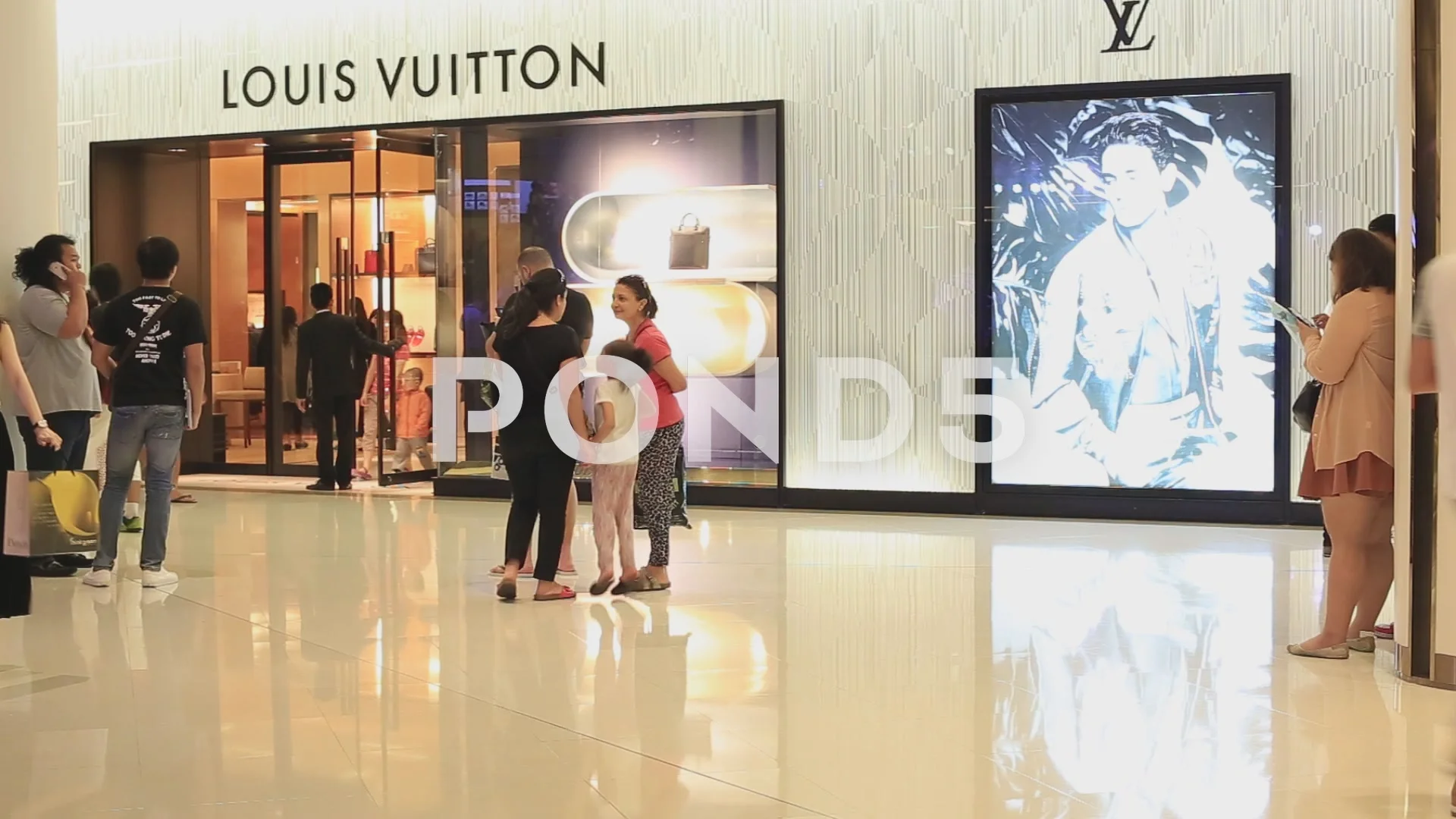 People seen walking past a Louis Vuitton store in the area of
