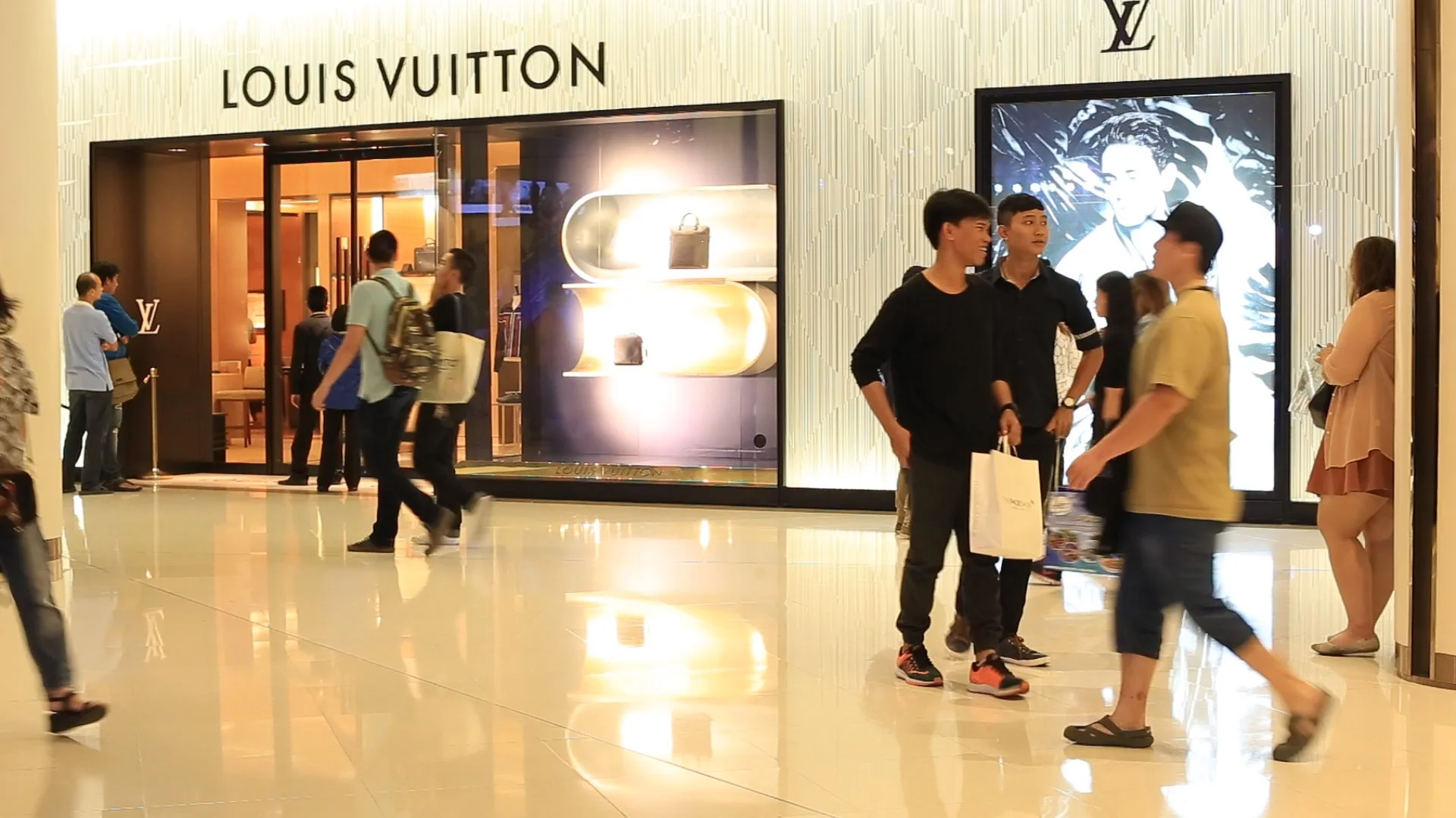 A person walking in front of a louis vuitton store photo – Free