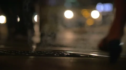 People walking over drain covers in night city Stock Footage 57178013