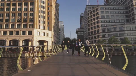 People walking over North Dock Footbridge sunset in Canary Wharf , London UK Stock Footage 147143495