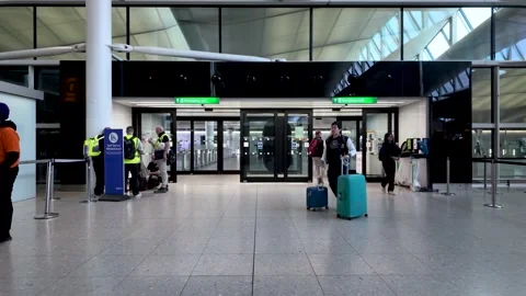 People walking past automatic doors at a modern airport terminal Stock Footage 320226204