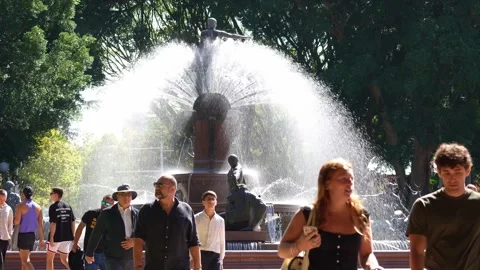 People walking past the large, spraying Archibald Fountain in sunlit Hyde Park Stock Footage 338010631