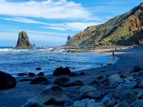 People walking on a remote dramatic beach in a volcanic African island Stock Photos