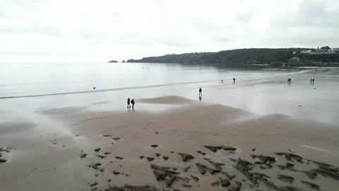 People walking on sandy beach, rocks rising out from sand Stock-Footage 166659998