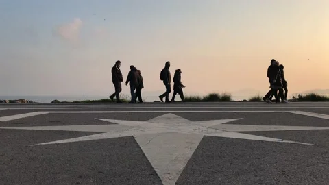People walking on seashore at sunset Stock Footage 144342325