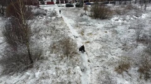 People walking on a snowy path in a rural area with cars parked nearby Stock Footage 329431865
