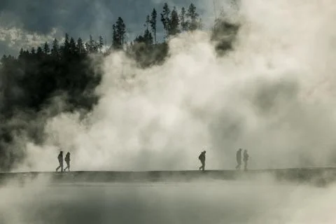 People walking through clouds of smoke / vapor from Yellowstone geysers Stock Photos