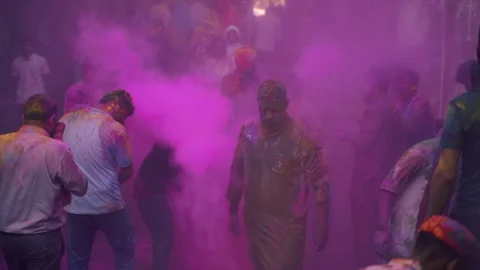 People walking through dense cloud of pink gulal powder during Holi in slow Stockbeeldmateriaal 341325316