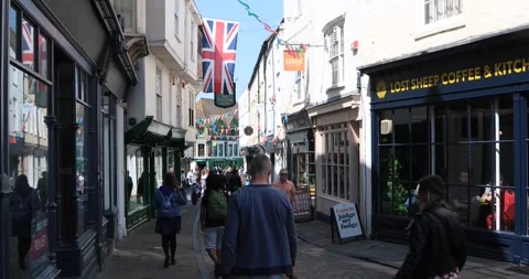People walking through flag-decorated historic street in Canterbury Stock Footage 321033083