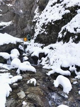 People walking through gorge next to mountain rive Stock Photos