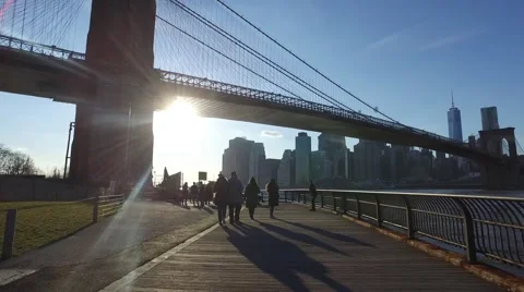 People walking under the Brooklyn Bridge on a beautiful sunny day Stock Footage 62781353