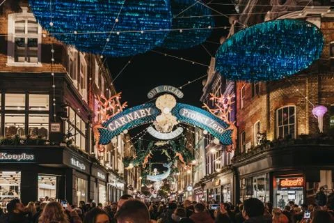 People walking under Project Zero sustainability themed Christmas lights in C Stock Photos