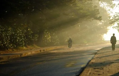 People walking under rays of the sun Stock Photos