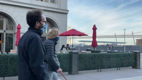 People walking by wearing masks while couple leaves Cafe SF Bay Bridge Stock Footage 144290309