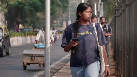 A people walking to work on a narrow sidewalk next to a busy road in Mumbai Stock Footage 327133726