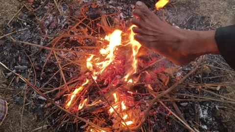 People warming their hands and feet over a glowing campfire. 库存影片 326651303