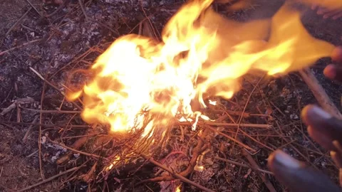 People warming their hands and feet over a glowing campfire. Видео 326651305