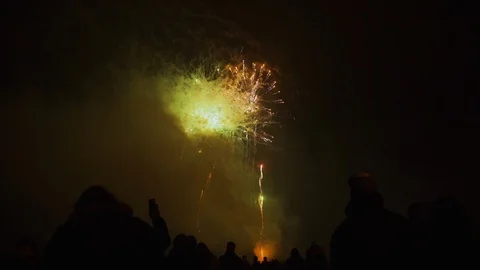 People watch fireworks exploding in the night sky as they gather at a Video stock 105064454
