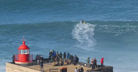 People watching the big giant waves near the Fort of Nazare Stock Footage 221582213