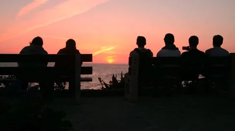 People watching sunset at beach from behind Stock Footage