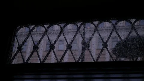 People in the window are walking in the rain, hiding under umbrellas. slow Stock Footage 78893520