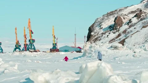 People in winter jackets ski along frozen sea by cranes 스톡 동영상 131797828