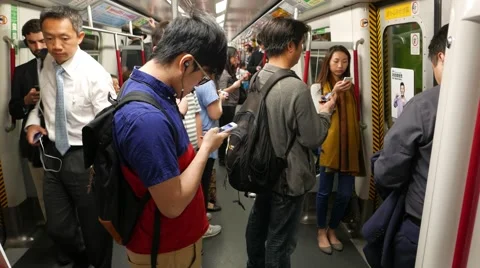 People within moving metro train, boy looking smart phone, man pass by Stock Footage