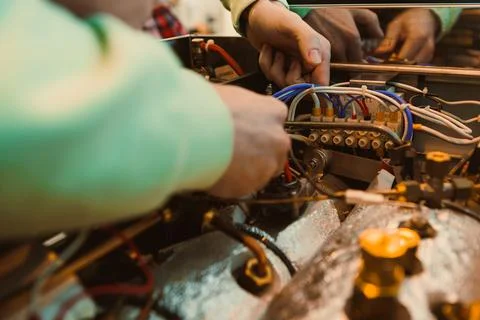 People work on a machine in a workshop while connecting and fixing wires to.. Foto stock