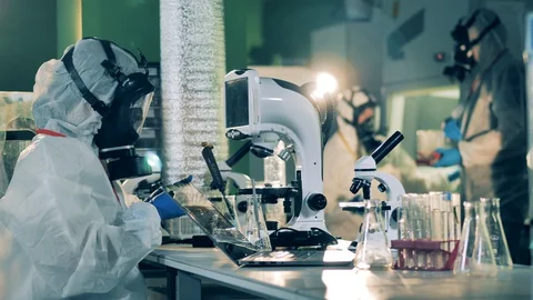 People work with microscopes in laboratory while developing a vaccine. Video stock 129521177