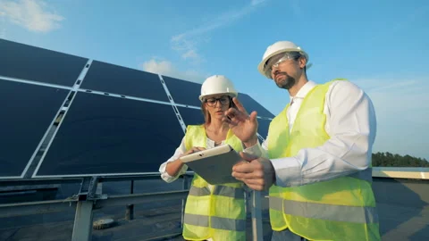 People work with a tablet while walking near solar panels, close up. Video stock 100969993