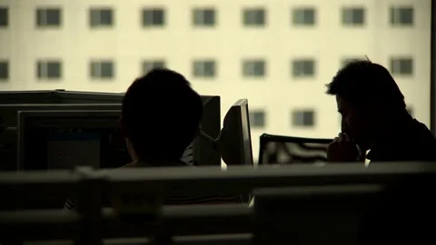 People working at computer terminals in silhouette backlit Stock Footage