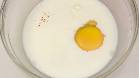 Pepper is add to egg with milk, slow motion. Closeup Stock Footage 76149596