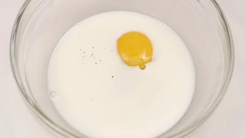 Pepper is added to egg with milk in slow motion Stock Footage 76147713