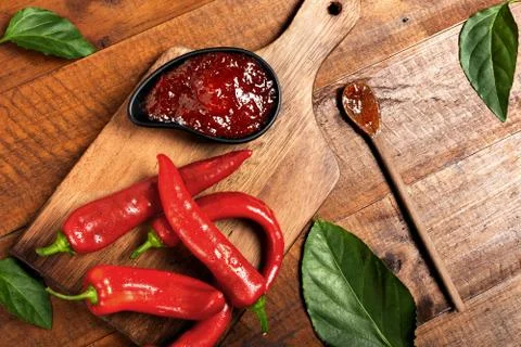Pepper jam on rustic wooden background with wooden spoon bottom right Stock Photos