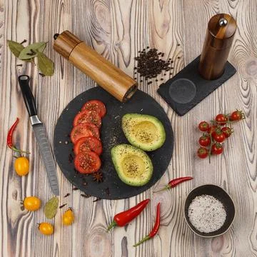 Pepper mill and salt mill on a wooden table with other products and a knife Stock Photos