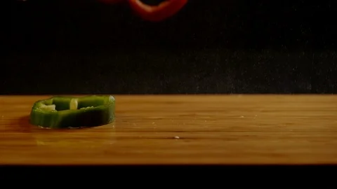 Pepper slices falling on wooden surface, Ultra Slow Motion Stock Footage 86575622