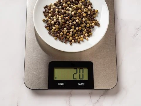 Pepper spice on a sauser over digital kitchen scales. Stock Photos