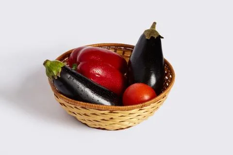Pepper, tomato and two black eggplants lie in the wattled plate Stock Photos