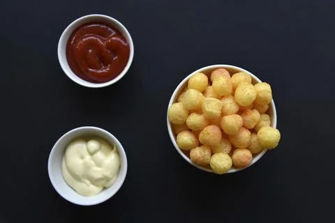 Peppered corn chips with sauce on a black background. Salty snack of corn sna Foto stock