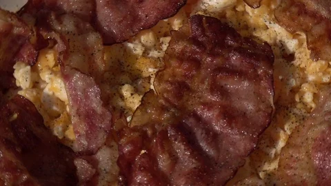 Peppered scrambled eggs and sliced crispy wavy bacon, rotating close up. Stock Footage 99851968