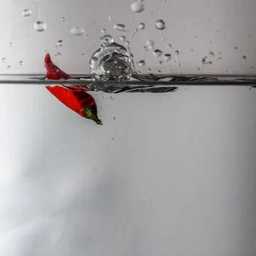 Pepperoni drops in water Stock Photos