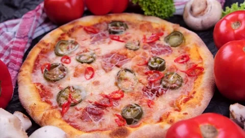 Pepperoni pizza with a background of vegetables on a black background Stock Footage 229689520